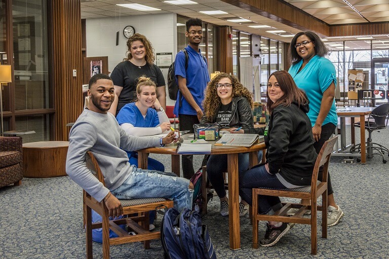 students at table posing in a library
