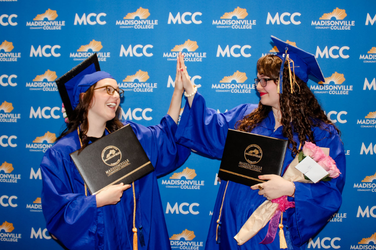 2 female graduates high fiving