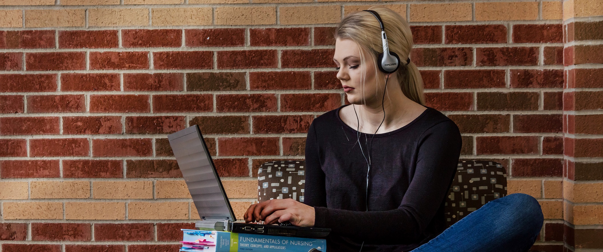 girl with headphones on laptop in chair.