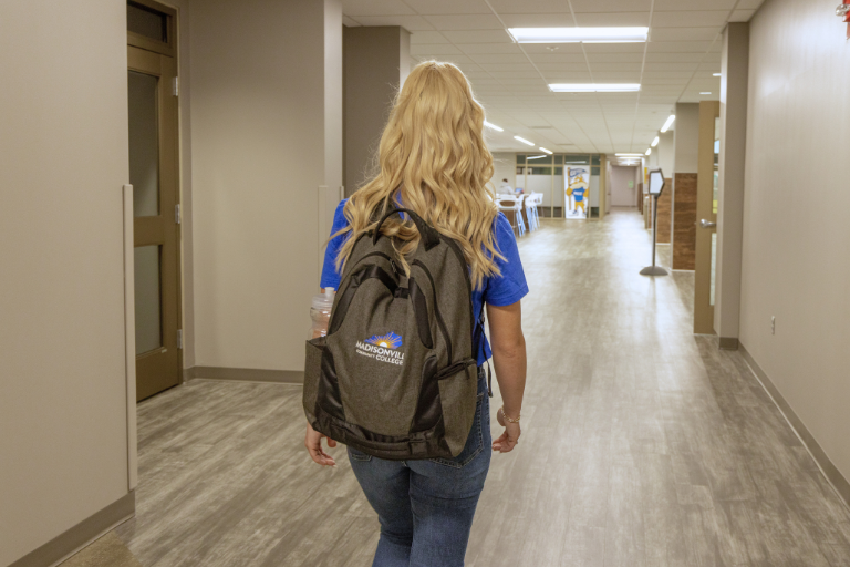 student walking down hall wearing backpack