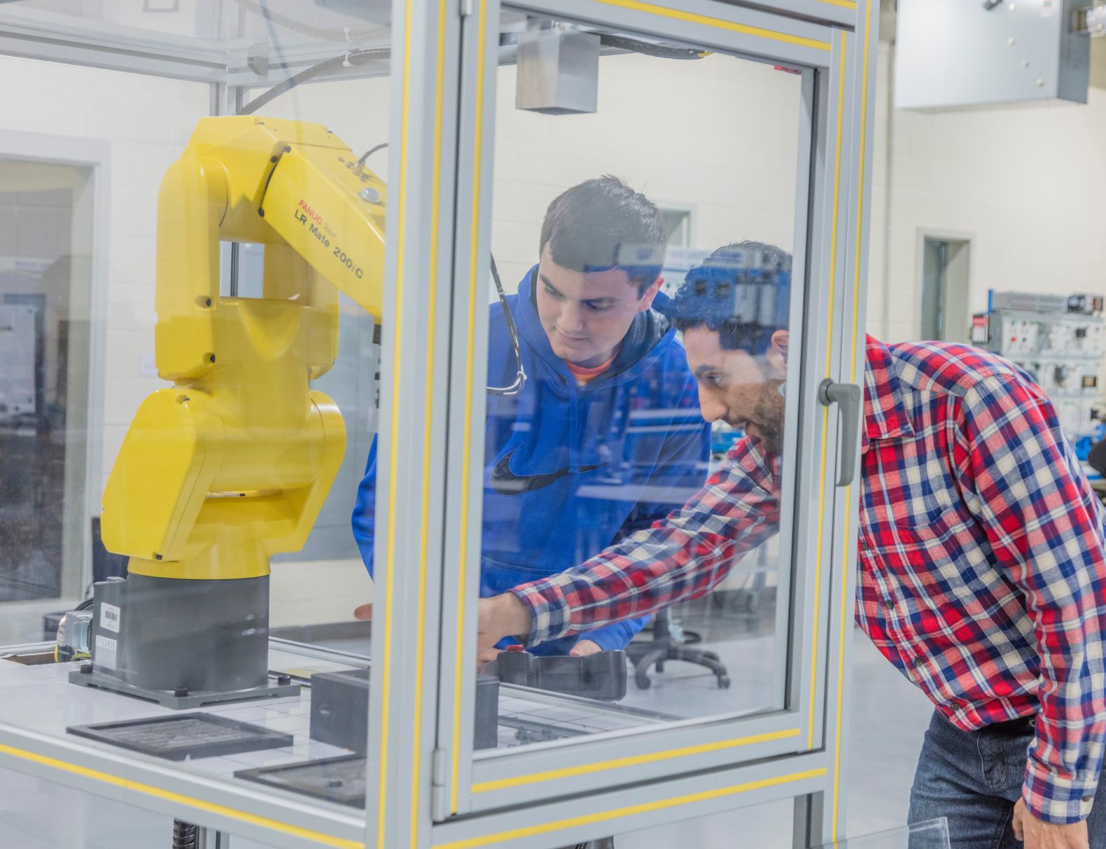 Students looking at a robotic arm. 